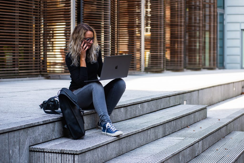 woman sitting on concrete stairs with a laptop in her lap